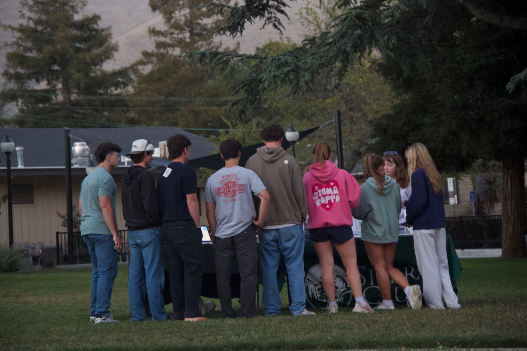 Students gathered around an information table in a park